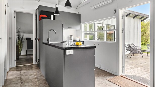 A modern kitchen with a central island, a built-in oven, and a large window providing natural light. - 2 bedroom nice home in Karrebæksminde (Karrebæksminde)