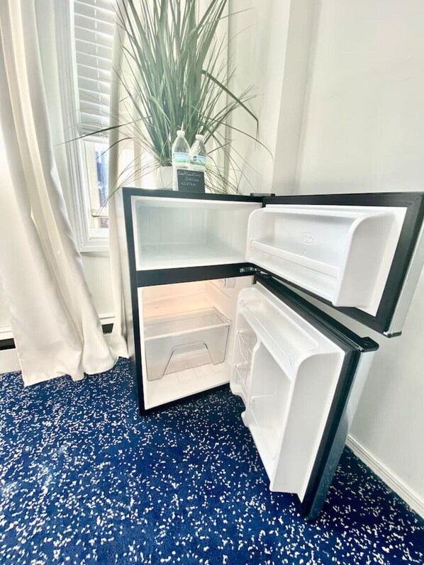 A corner refrigerator with a freezer compartment, a water dispenser, and a small shelf.