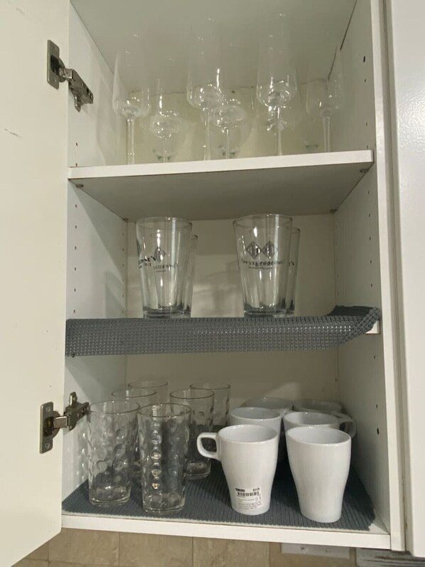 A cabinet with shelves holding various glassware and mugs.