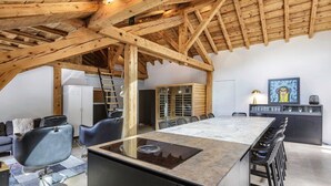 Una cocina moderna con una isla grande, vigas de madera y un comedor con taburetes de bar.