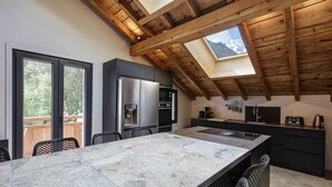 Una cocina moderna con una isla grande, electrodomésticos integrados y un tragaluz.