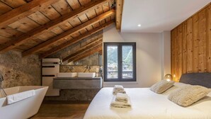 Un dormitorio con una cama grande, una bañera, un lavabo y una ventana.