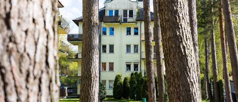A multi-story building with balconies, surrounded by trees.