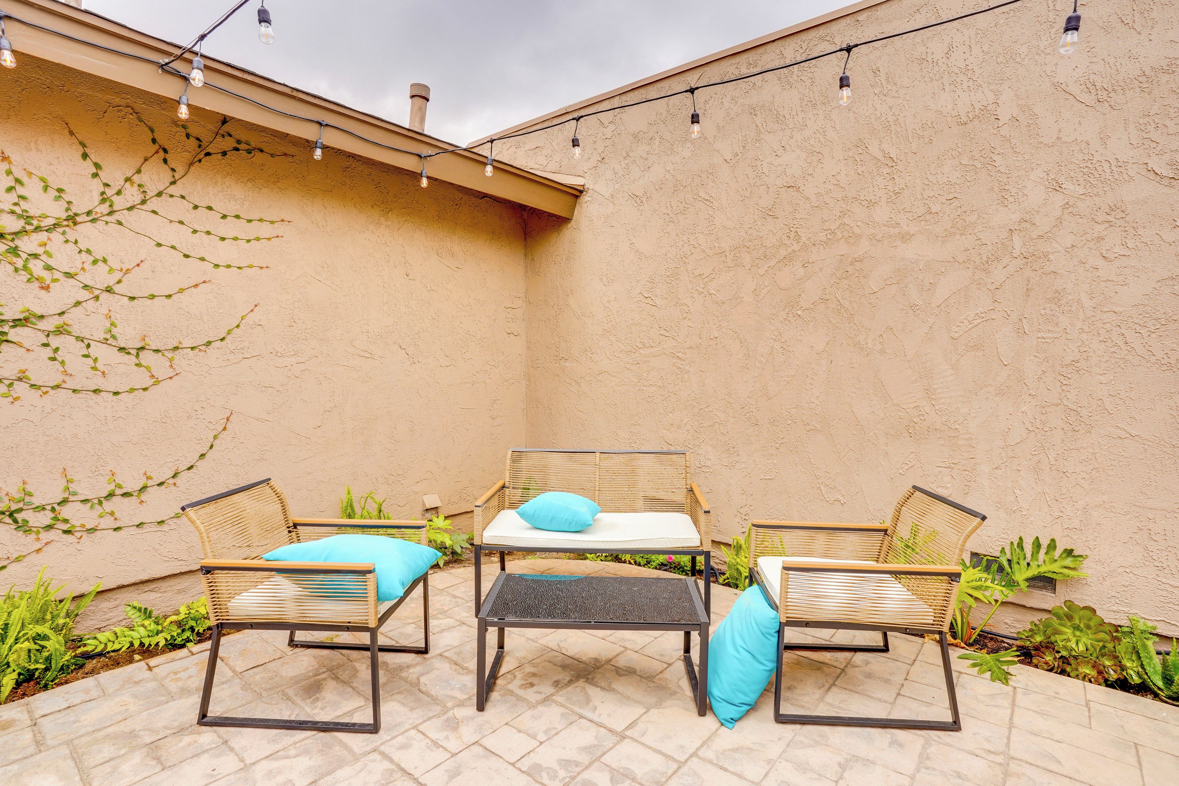 Eine Terrasse mit Korbmöbeln, einem Tisch und Lichterketten.