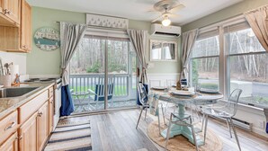 A kitchen with wooden cabinets, a large window, and a dining area with clear chairs. - ‘Livin Wells' Retreat, 2 Mi to Drakes Island Beach (Wells)