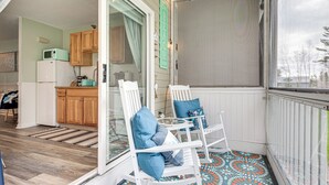 A porch with a rocking chair and a table, a kitchen in the background, and a decorative sign. - ‘Livin Wells' Retreat, 2 Mi to Drakes Island Beach (Wells)