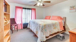 Une chambre à coucher avec un lit, un bureau, une chaise, un ventilateur de plafond et un calendrier accroché au mur.