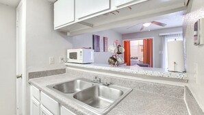 Une cuisine équipée de deux éviers en acier inoxydable, d’un four à micro-ondes blanc et d’un ventilateur de plafond.