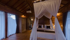 Una cama con dosel sobre cuatro postes en una habitación de madera con un ventanal y cortinas.
