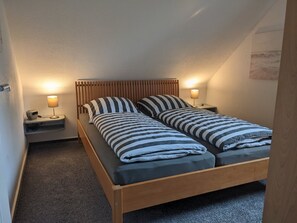 Un letto singolo con testiera in legno, due lampade ai lati del letto e un comodino con una lampada.