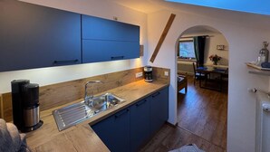 Eine kleine Küche mit blauen Schränken, einer Kaffeemaschine und einem Oberlicht.