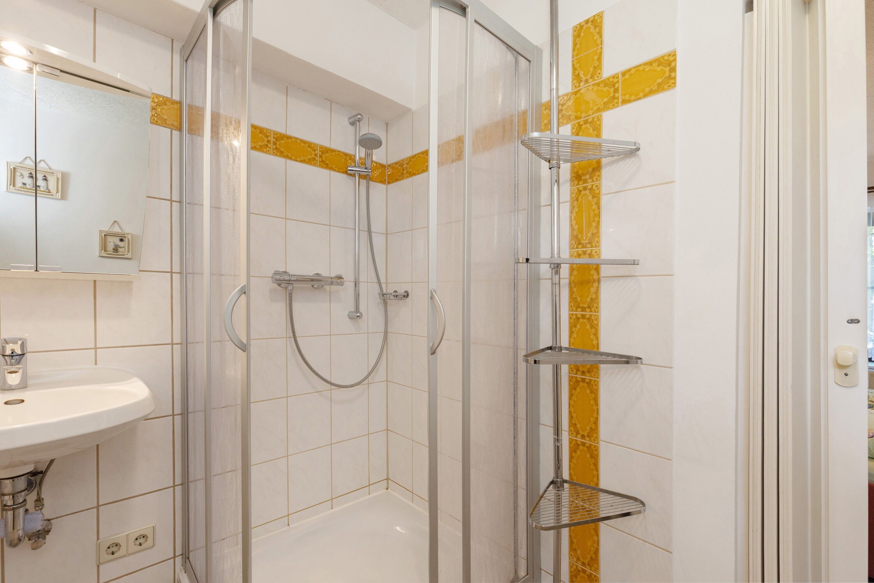 Ein Badezimmer mit einer Duschkabine, einem Waschbecken und einem Spiegel.