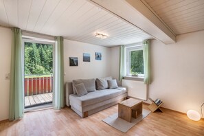 A room with a sofa, a coffee table, a radiator, and a window with curtains.