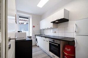 A compact kitchen with a washing machine, oven, and a refrigerator.