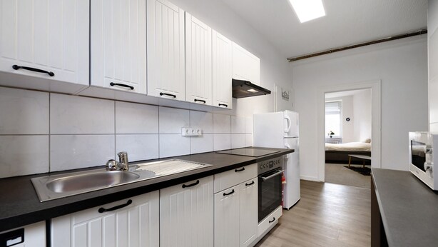 A modern kitchen with white cabinets, a black countertop, and a built-in oven.