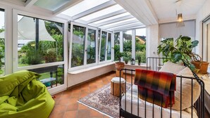 A sunroom with large windows, a bench, a colorful blanket, and potted plants. - Apartment 'Schwarzwald Glück Ferienwohnung' with Private Terrace and Wi-Fi (Bühl)