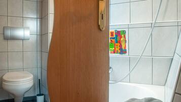 Une salle de bain avec des toilettes, une douche et un porte-serviettes.