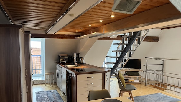 Une cuisine compacte avec un coin repas, un lave-linge et un escalier menant à un niveau supérieur.