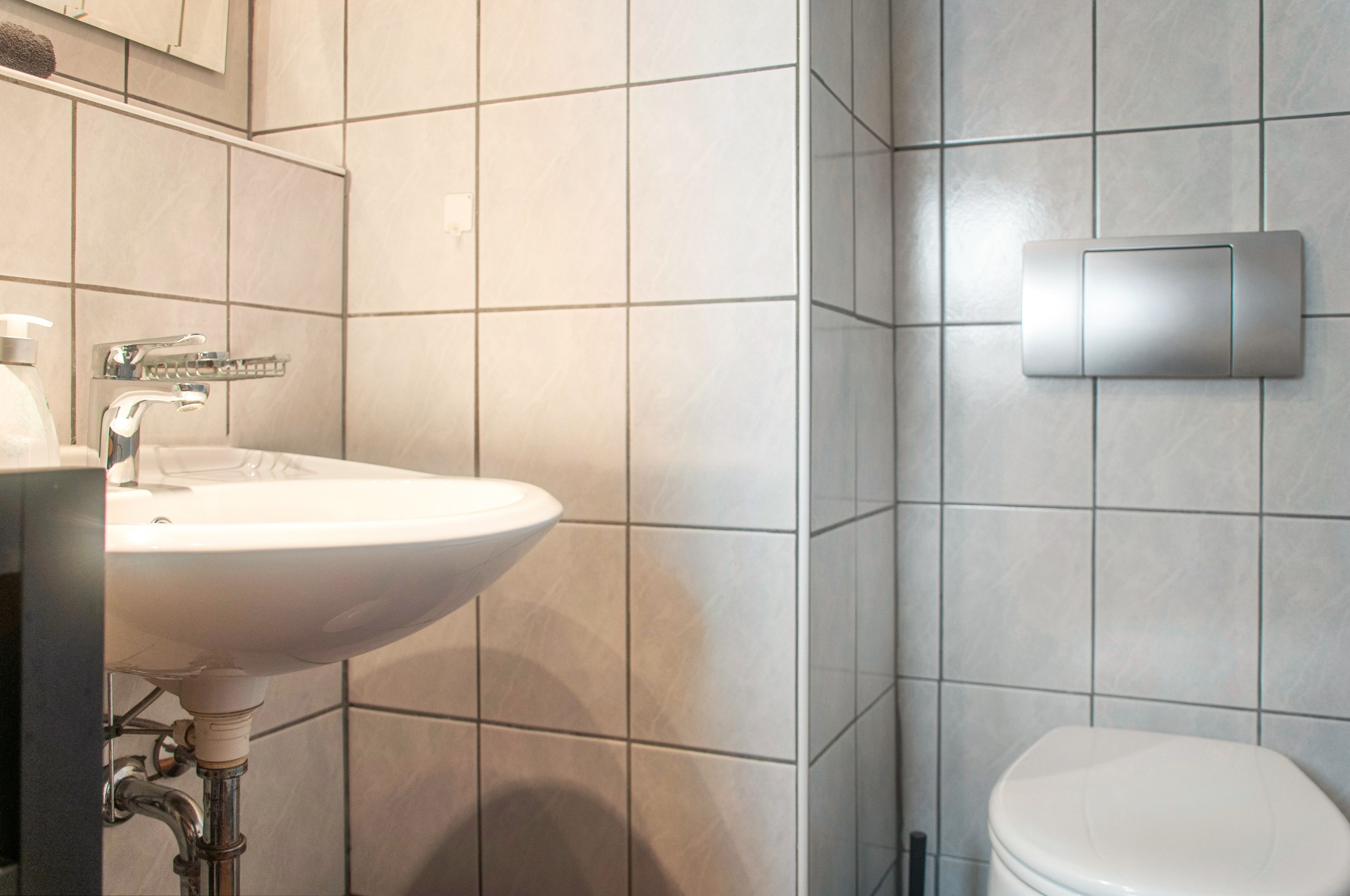 A bathroom with a white sink, a toilet, and a wall-mounted light fixture.