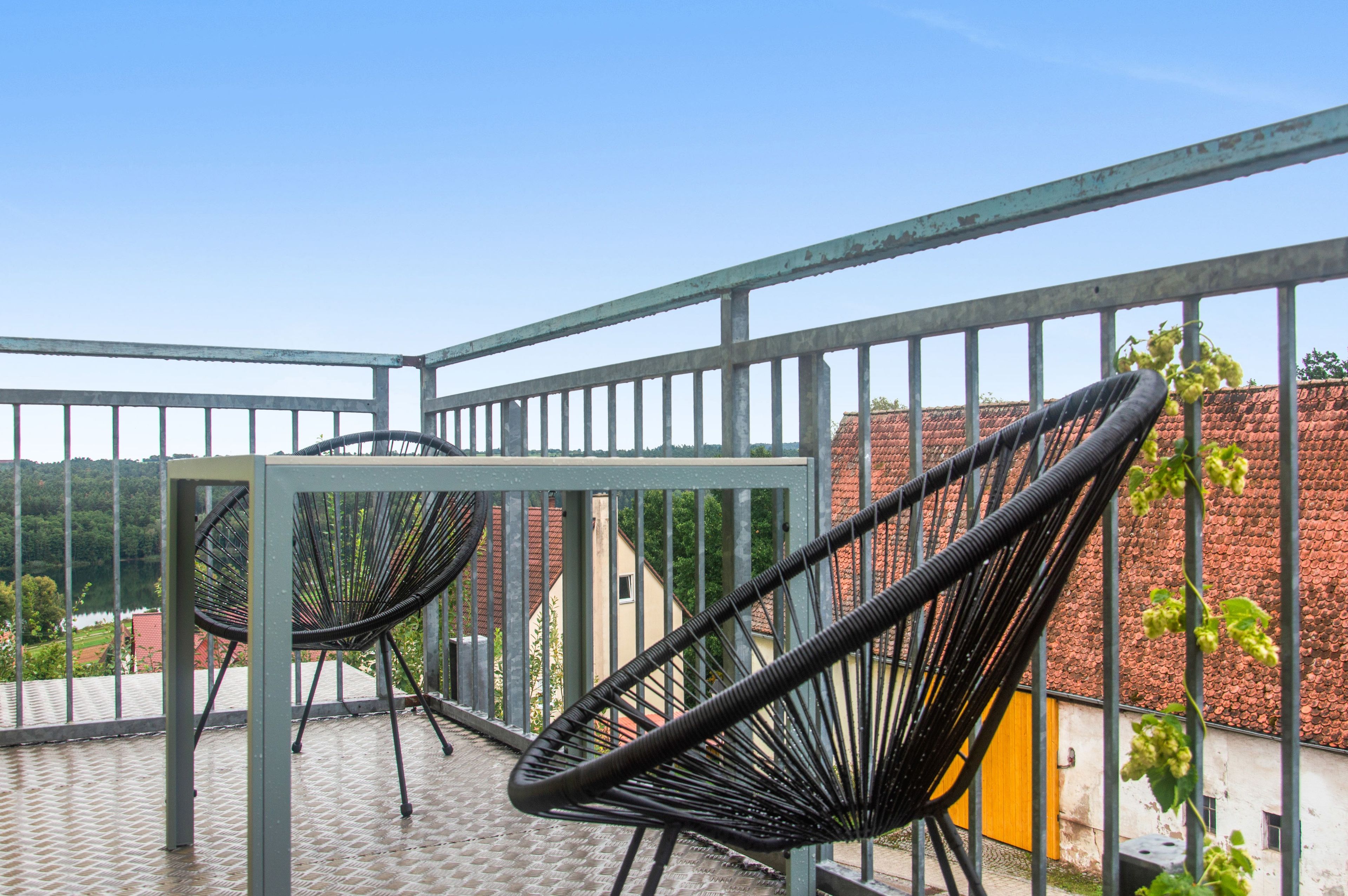 A balcony with metal railings, a table, and two black chairs.