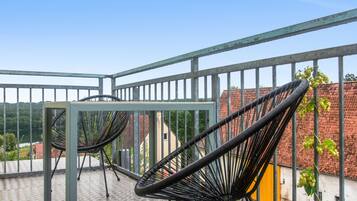 A balcony with metal railings, a table, and two black chairs.