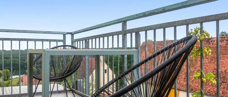 A balcony with metal railings, a table, and two black chairs.