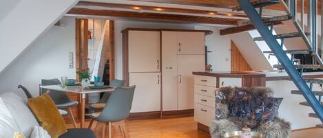 A modern interior with a dining area, kitchen, and a staircase.