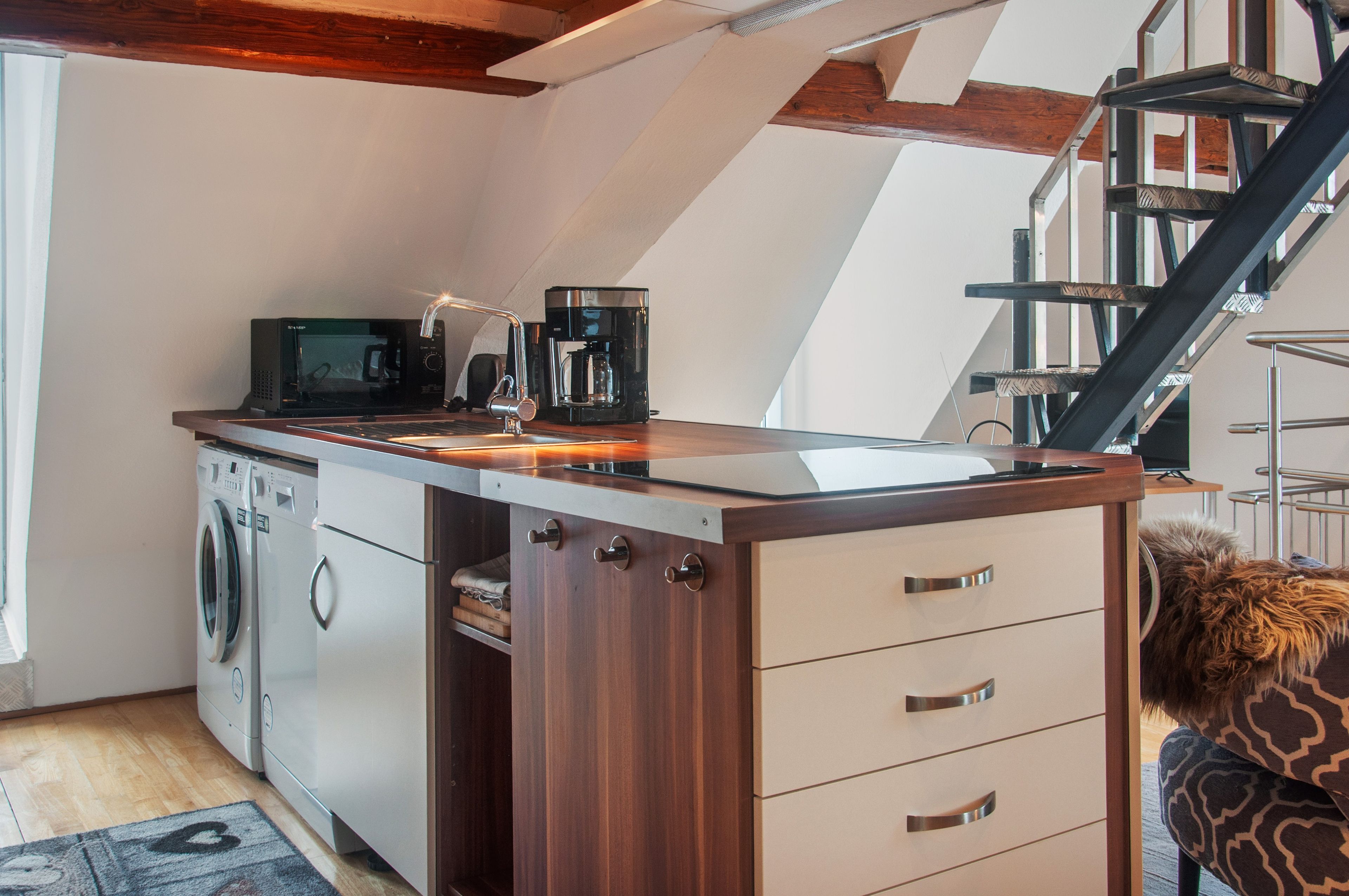 Una cucina compatta con lavatrice, macchina del caffè e forno a microonde.