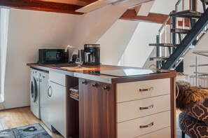 A compact kitchen with a washing machine, a coffee maker, and a microwave. - Gallery Apartment with Lake View, Balcony, and Wi-Fi (Absberg)