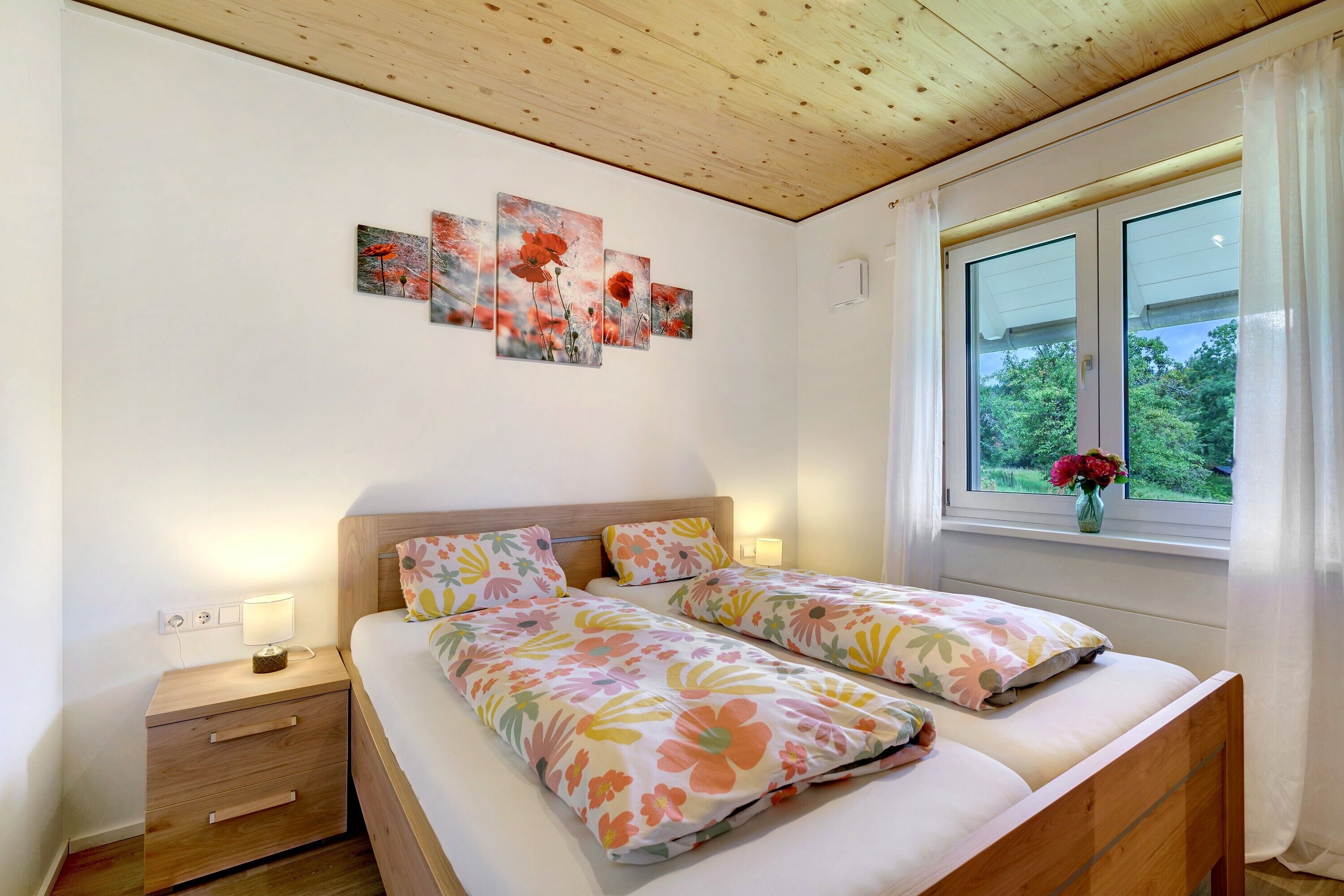 Un dormitorio con dos camas, techo de madera, una ventana con cortinas y decoración en la pared.