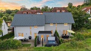 A two-story house with a grey roof, a patio with outdoor furniture, and a small shed. - Holiday Home for up to 6 Guests with Pool and Sauna (Freudenstadt)