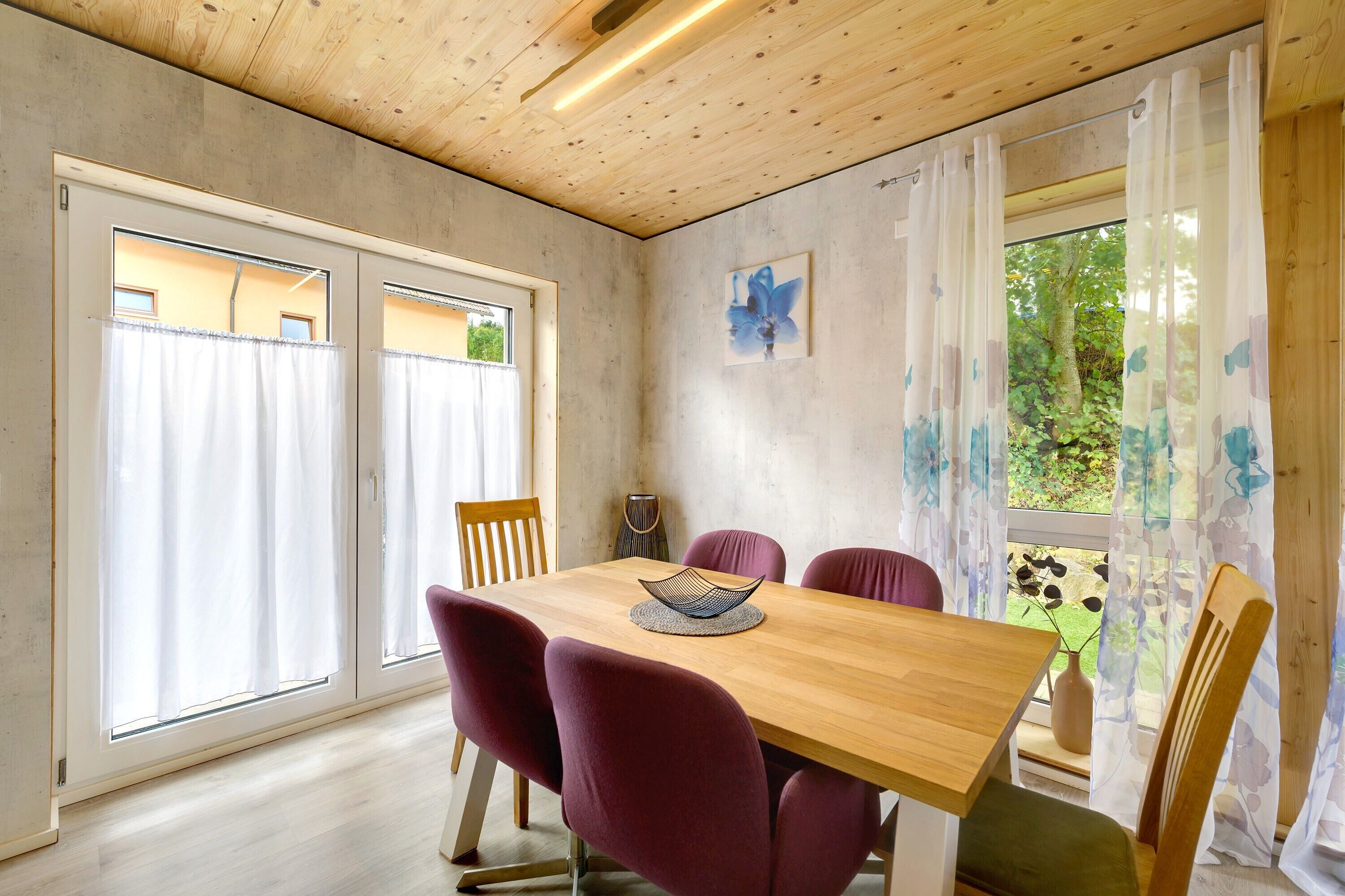 A dining area with a wooden table, purple chairs, and a vase with flowers.