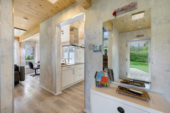 Un intérieur moderne comprenant une cuisine, un coin repas et une fenêtre donnant sur un espace verdoyant.