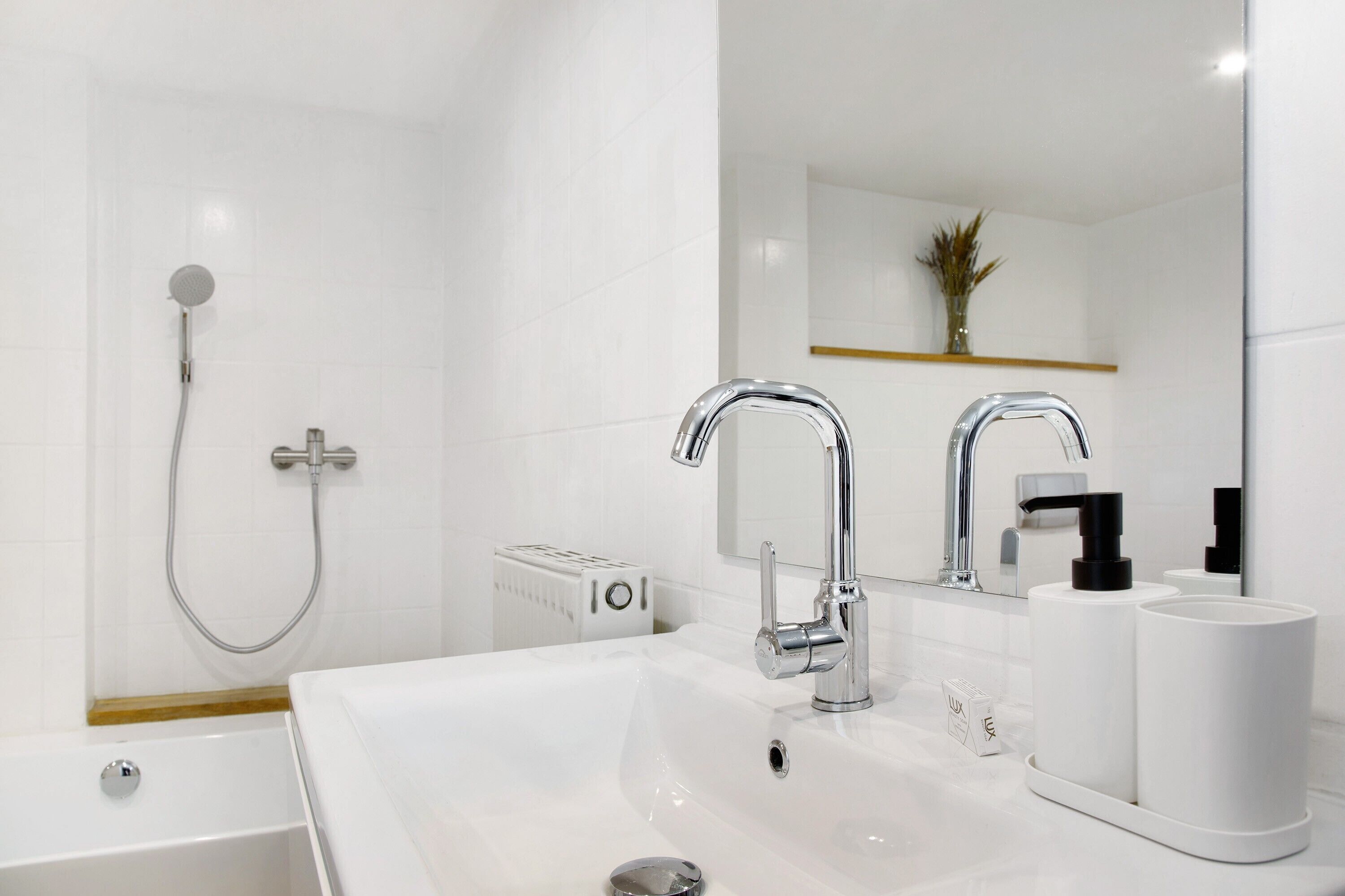 A modern bathroom with a bathtub, a sink with a mirror, and a shower head.