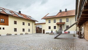 Sisäpiha, jossa on mukulakivilaatoitus, keskeinen suihkulähde sekä rakennuksia, joissa on puusta tehdyt julkisivut ja tiilikatteet.