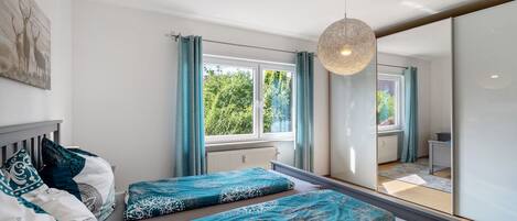Une chambre avec deux lits, un grand miroir et une fenêtre avec des rideaux.