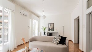 A modern living room with a sofa, a coffee table, and a view of the outdoors. - Acropolis Sunlight 2BR Aparment (Athina)