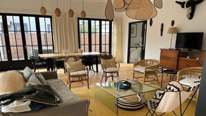 Een ruime woonkamer met een bank, stoelen, een salontafel en een eettafel.