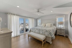 Une chambre à coucher comprenant un lit, un banc, une table de chevet et un ventilateur de plafond.