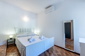 Hotellihuone, jossa on sänky, yöpöytä ja peili.