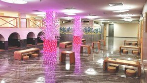 Un vestíbulo con zonas de estar, una recepción y elementos decorativos como flores rosas iluminadas.