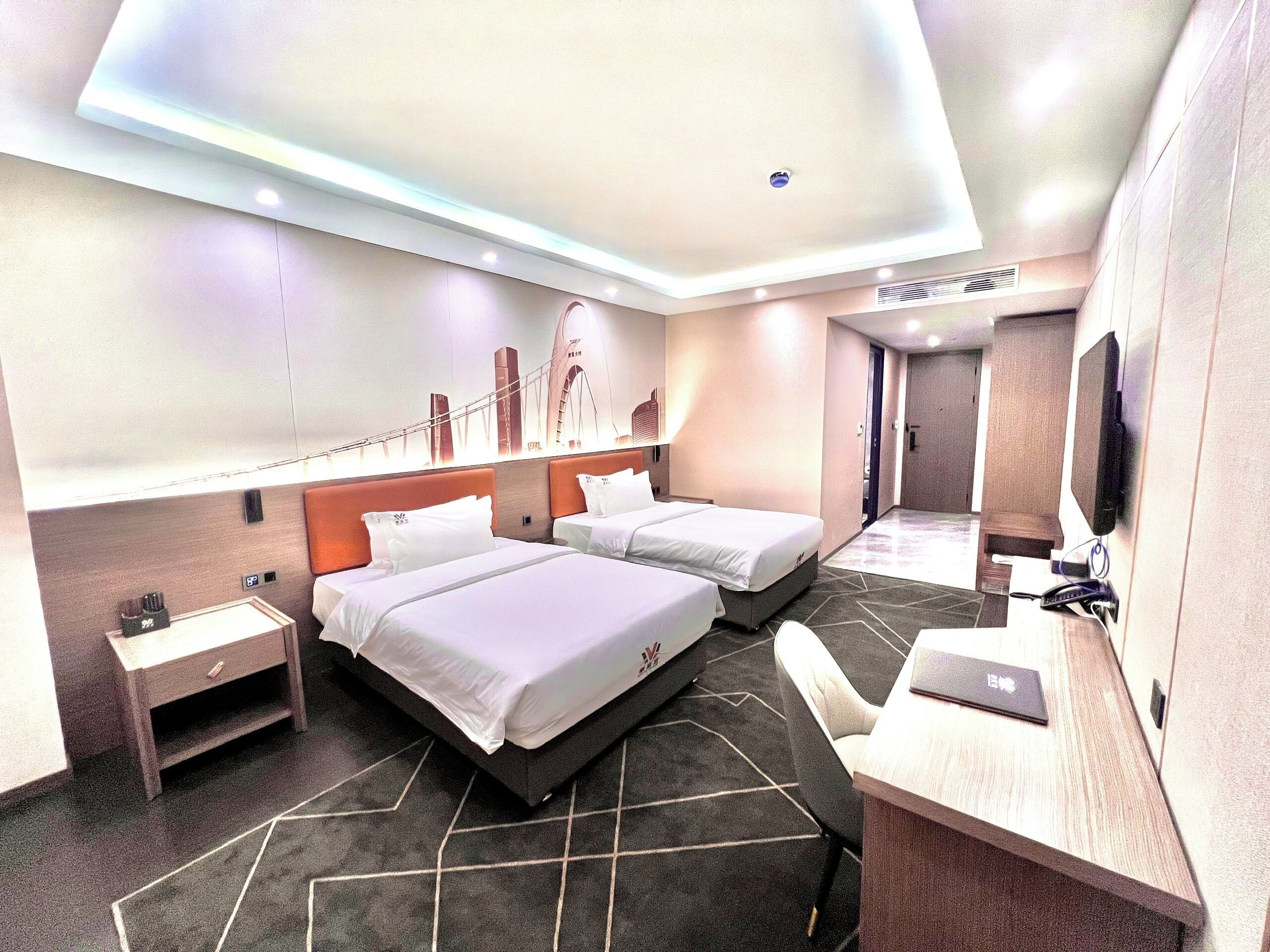 A modern hotel room with two beds, a desk, a chair, and a TV.