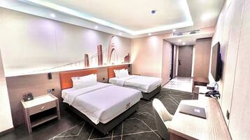 A modern hotel room with two beds, a desk, a chair, and a TV.