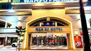 Exterior del Hotel Wah Fu Palace, con una entrada destacada y señalización iluminada.