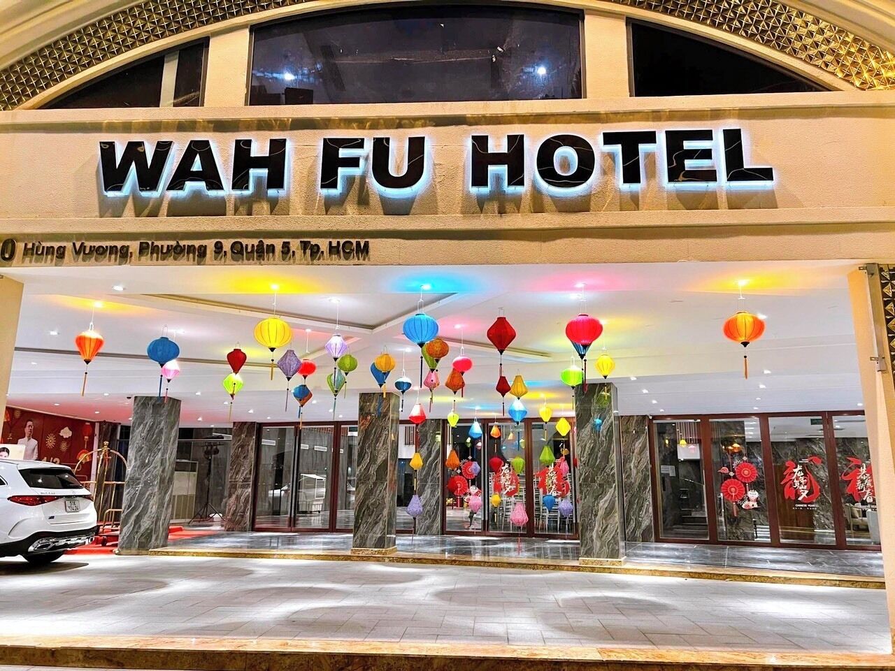 L’entrée de l’hôtel Wah Fu, avec sa façade moderne, ses colonnes de marbre et ses lanternes colorées suspendues.