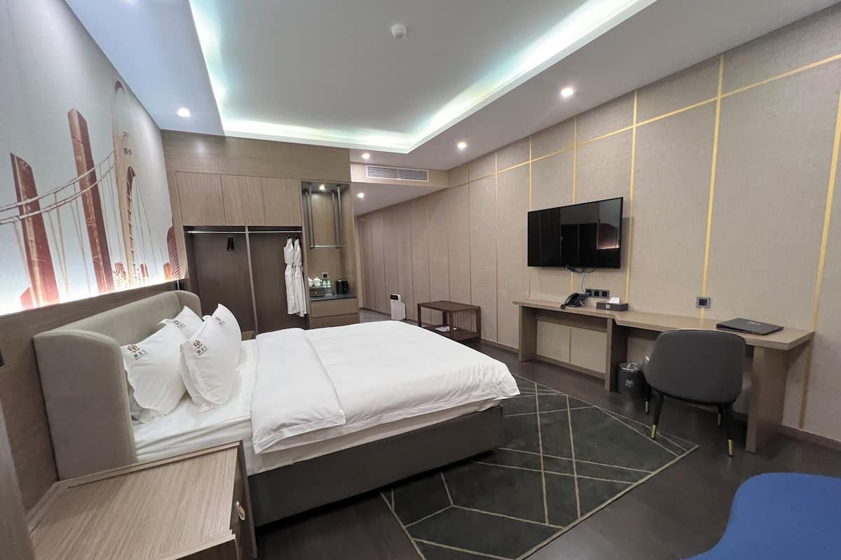 Une chambre d’hôtel moderne équipée d’un lit, d’un bureau, d’une chaise et d’un téléviseur.