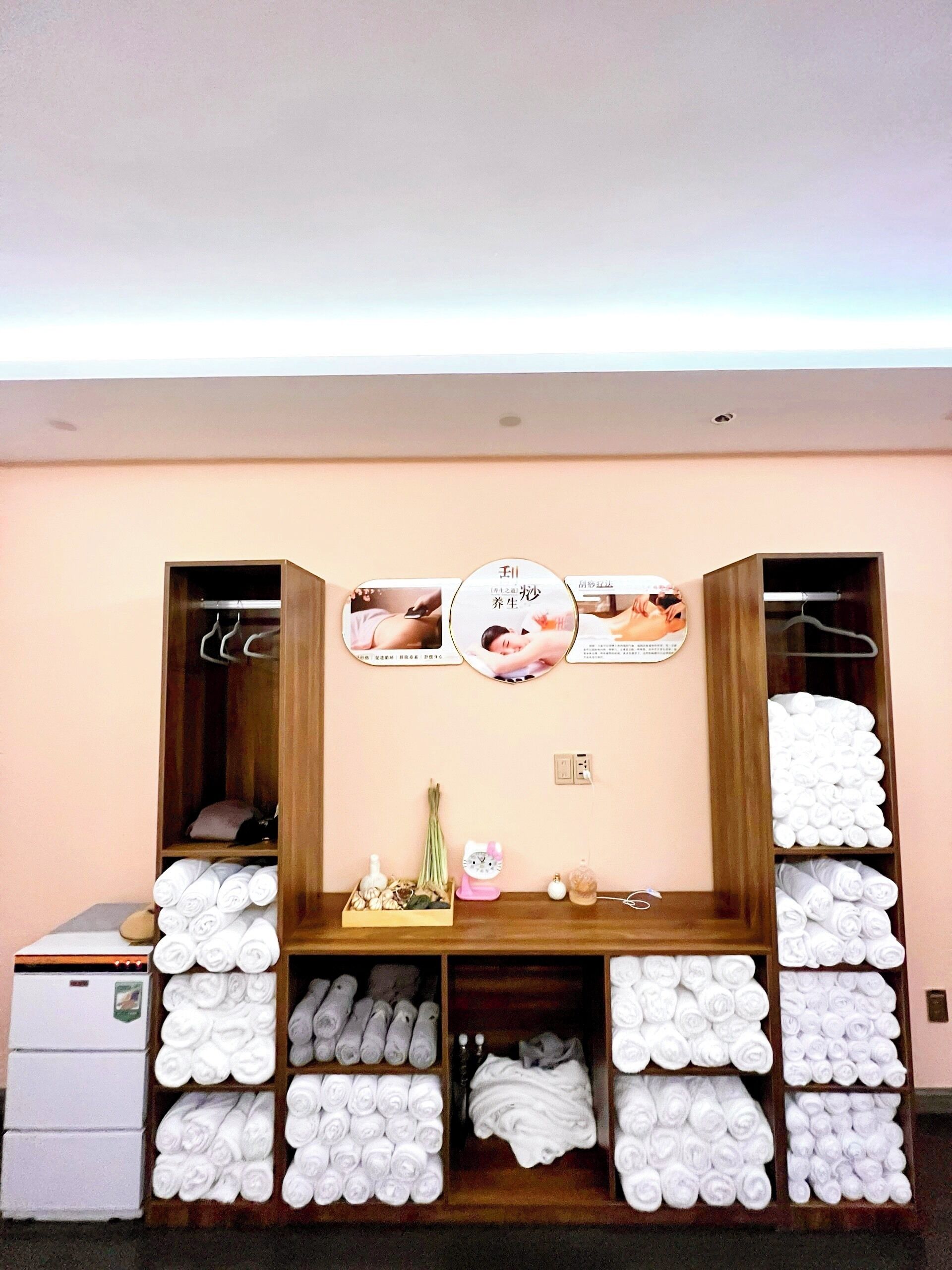 Habitación de hotel con un armario de madera, una mesita con artículos de aseo y toallas ordenadamente dobladas.