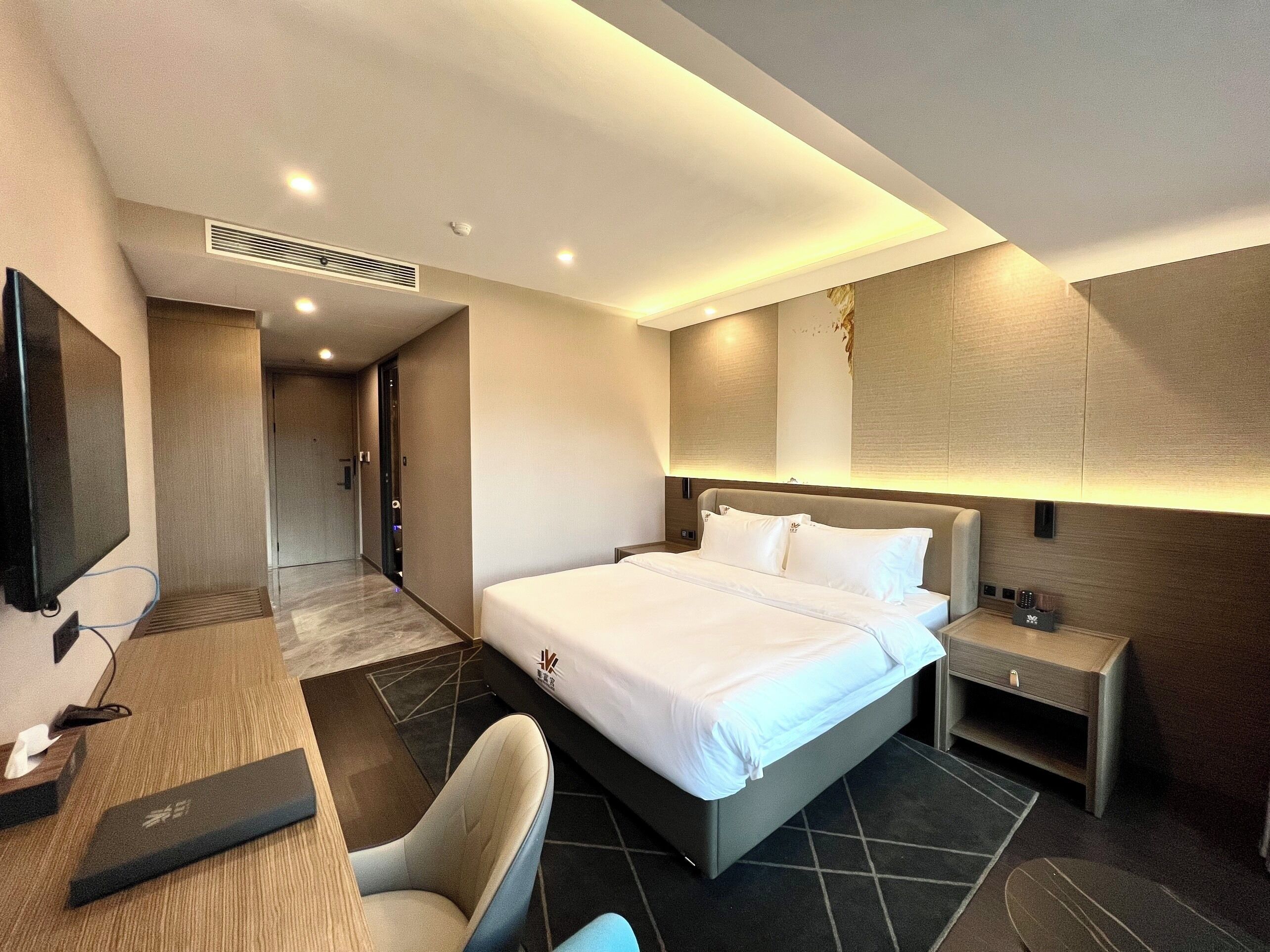 Une chambre d’hôtel avec un grand lit, un bureau avec un ordinateur, une chaise, une table de chevet et un téléviseur.