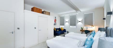 A modern bedroom with a large bed, a desk, a sofa, and a wardrobe.