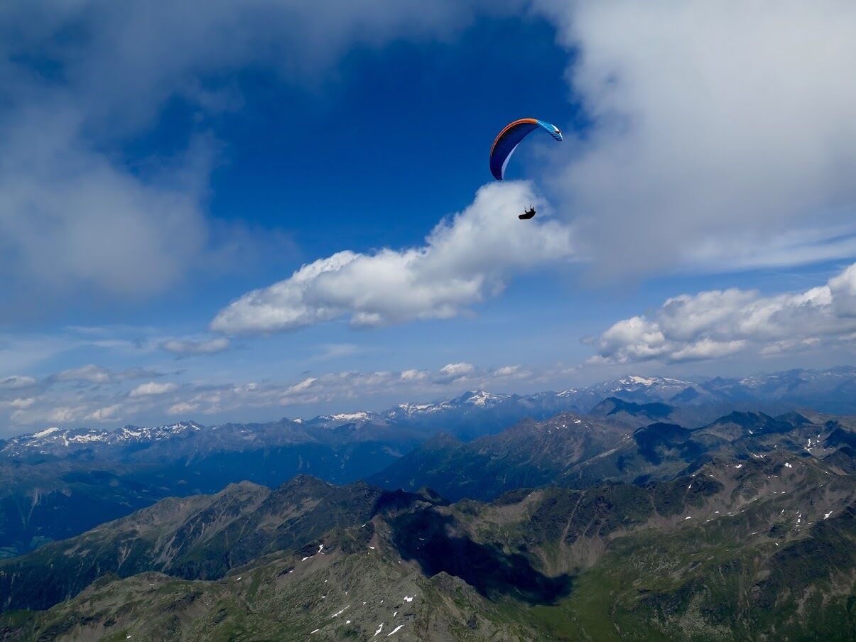 Een bergachtig landschap met een paraglider in de lucht.